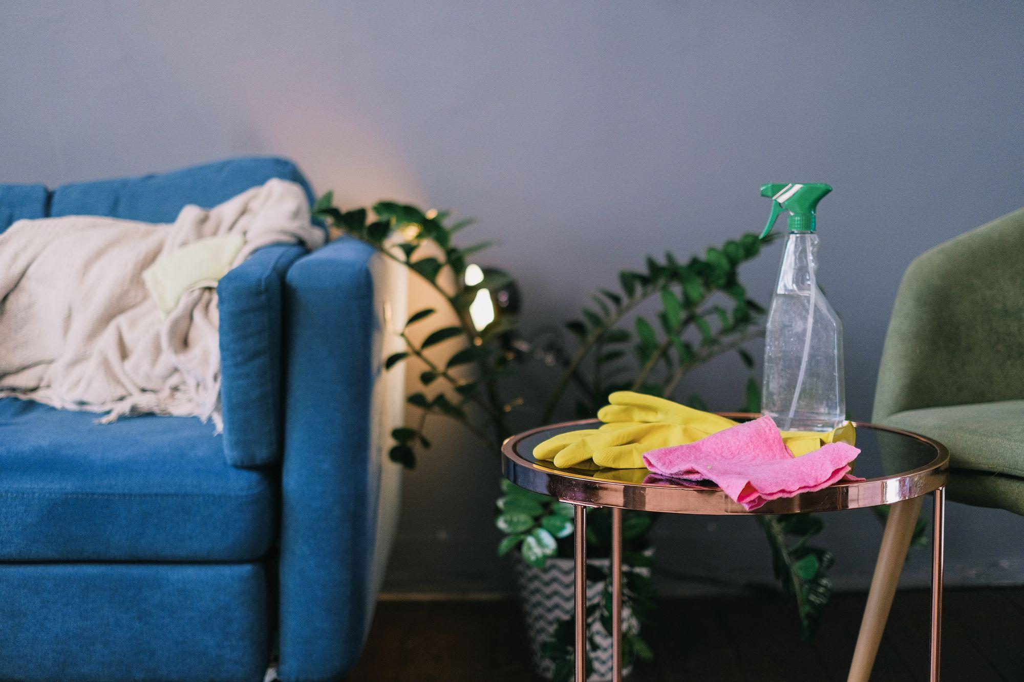 Cleaning supplies beside a blue sofa in a living room